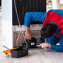 Tècnic de reparació treballant sobre un aparell domèstic.
